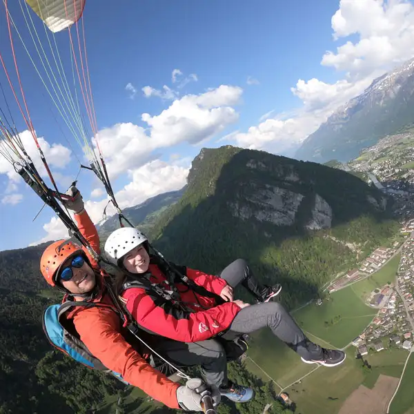 A girl floating down with a parachute at the end of a tandem skydive