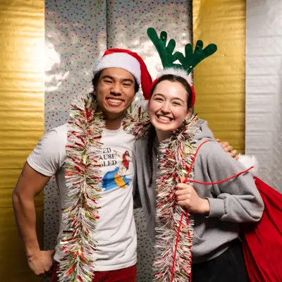 Two students in holiday dress-up smile for a photo