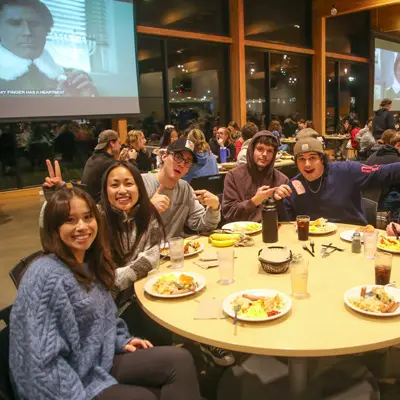a table of students smiles for a photo at Late Night breakfast