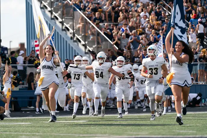 George Fox cheerleaders and football players rushing the field before the homecoming game
