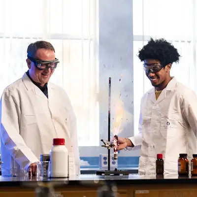 Student and professor working together with an explosion coming from a lab tube