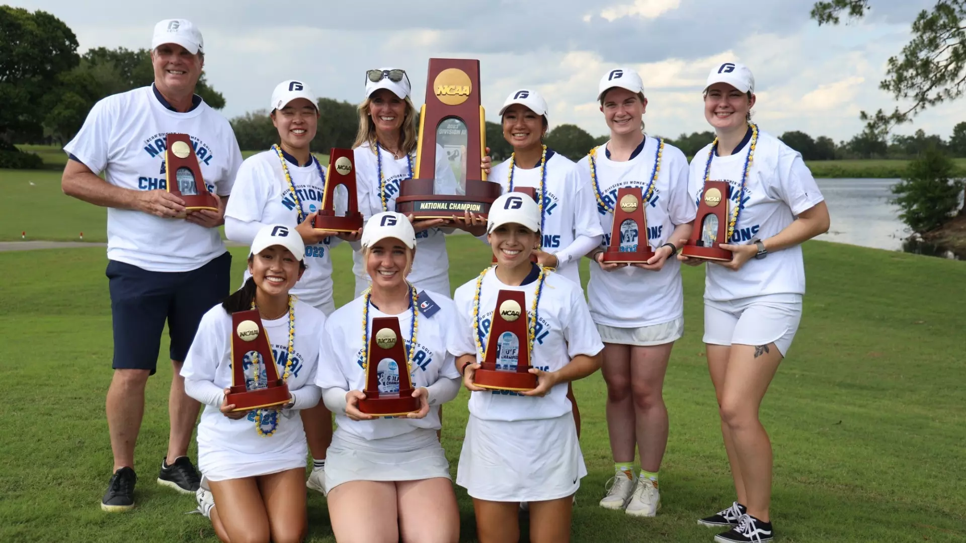 The women's golf team standing with their NCAA National Champion trophies