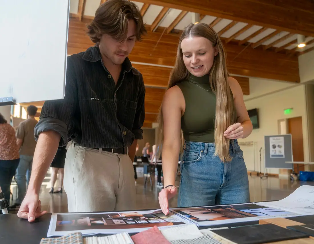 A student explaining something to a fellow student as she showcases her design work