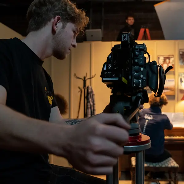 Michael pointing the camera towards a set with a guy playing piano