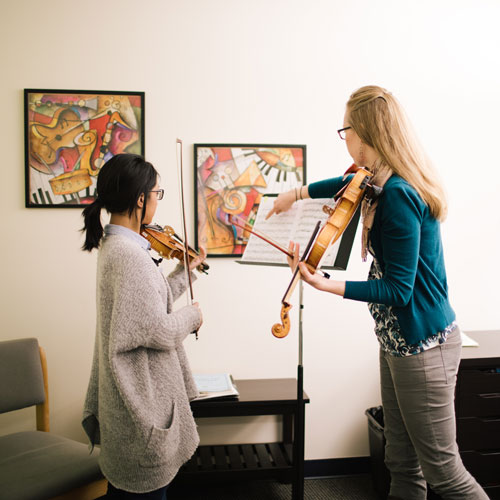 Student practices the violin in a practice room.