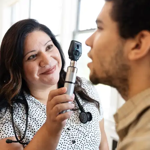 a PA student using an ophthalmoscope to care for a patient