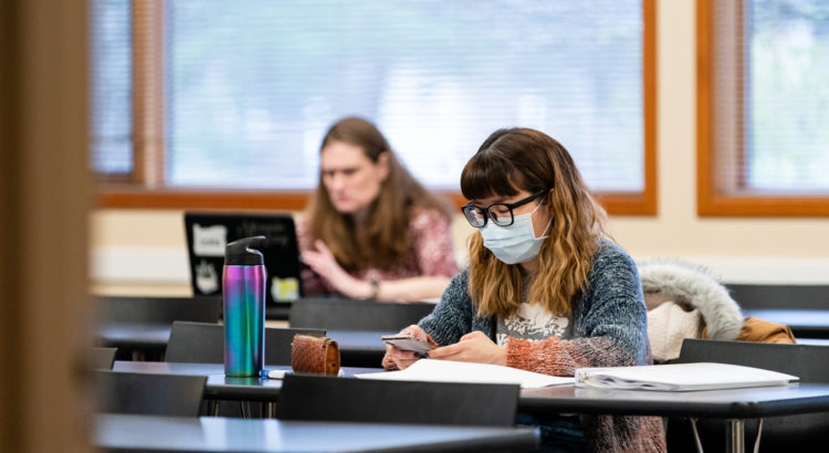 A student who is wearing a mask in a classroom studying