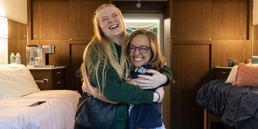 A student and RA hugging in a dorm room