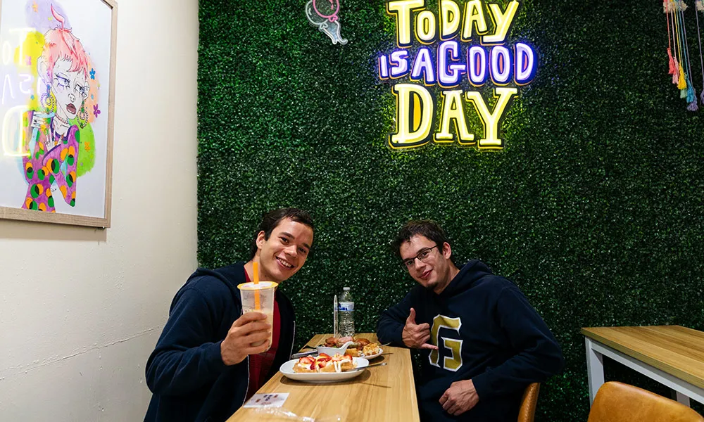 Two George Fox students eat waffles and share a drink at a shop downtown.