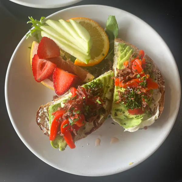 A plate of food including two halves of fancy avocado toast