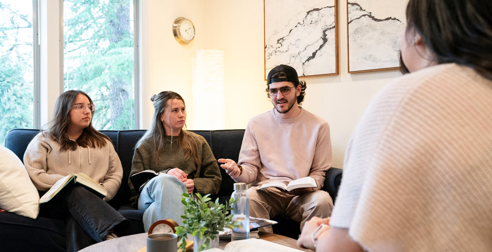 Ryan speaks in a life group while holding a bible