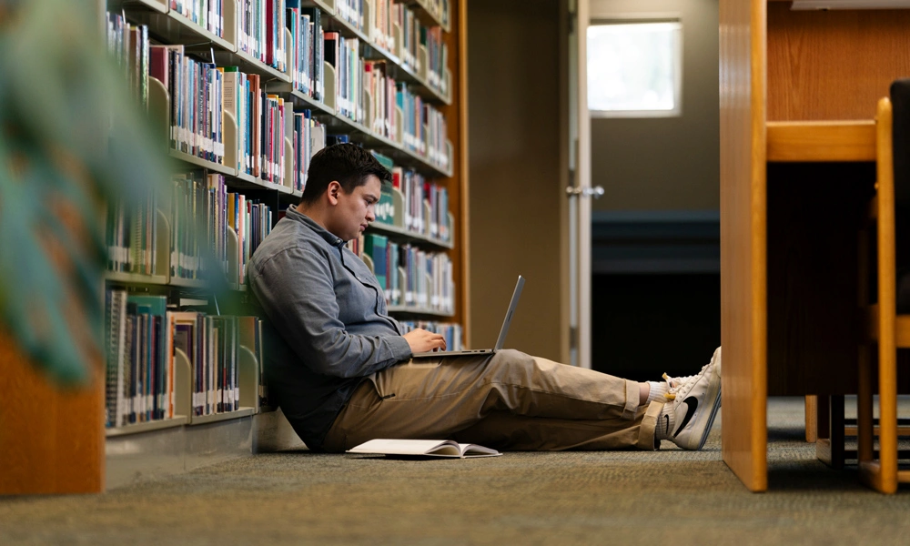 student on working on their laptop in the library
