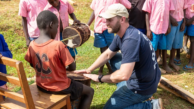 Trevor Owen playing the drums with children on a mission