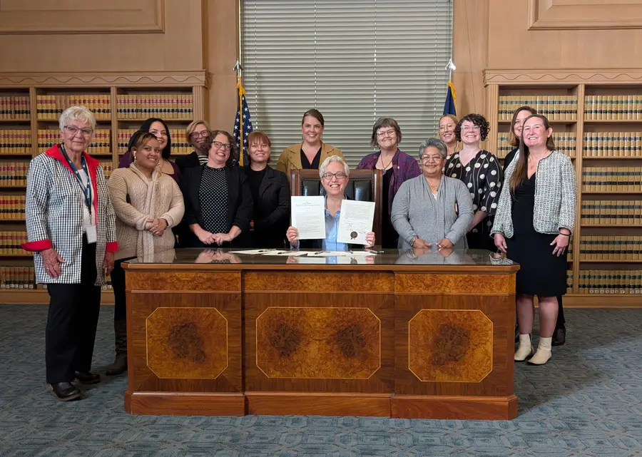 Lisa Jones stands wit other women around Tina Kotek's desk after the senate hearing