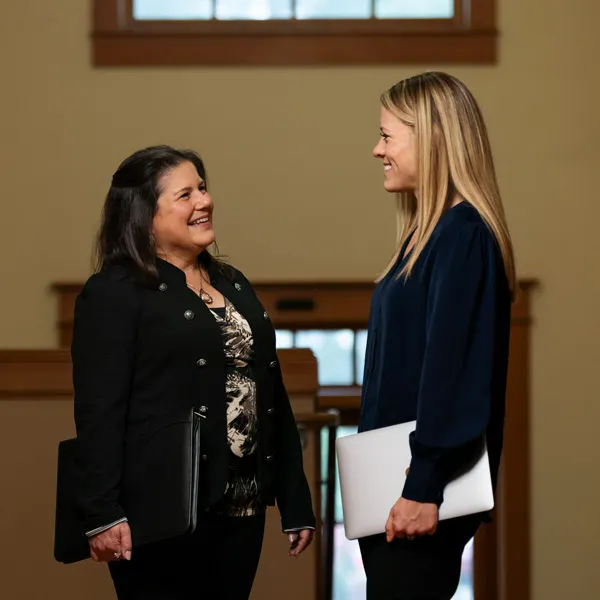 DBA student talks with a colleague while holding laptops 