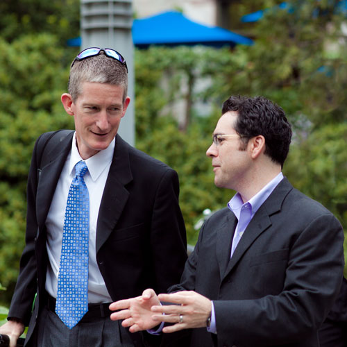 Two business men in suits have a conversation outside