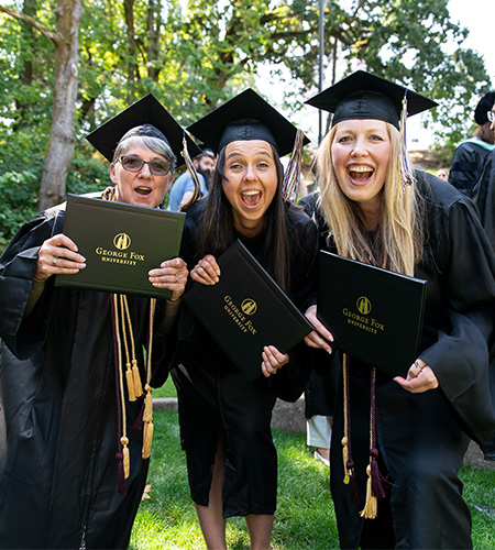 Students in graduation gowns holding diplomas