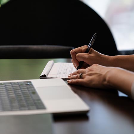 the hands of a woman writing on paper