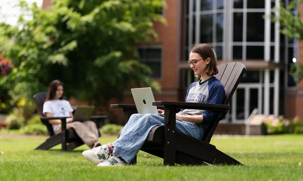 George Fox student works on a laptop outside