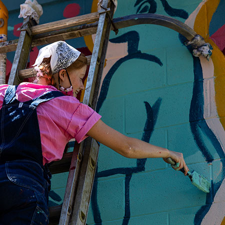 Art student painting a community mural