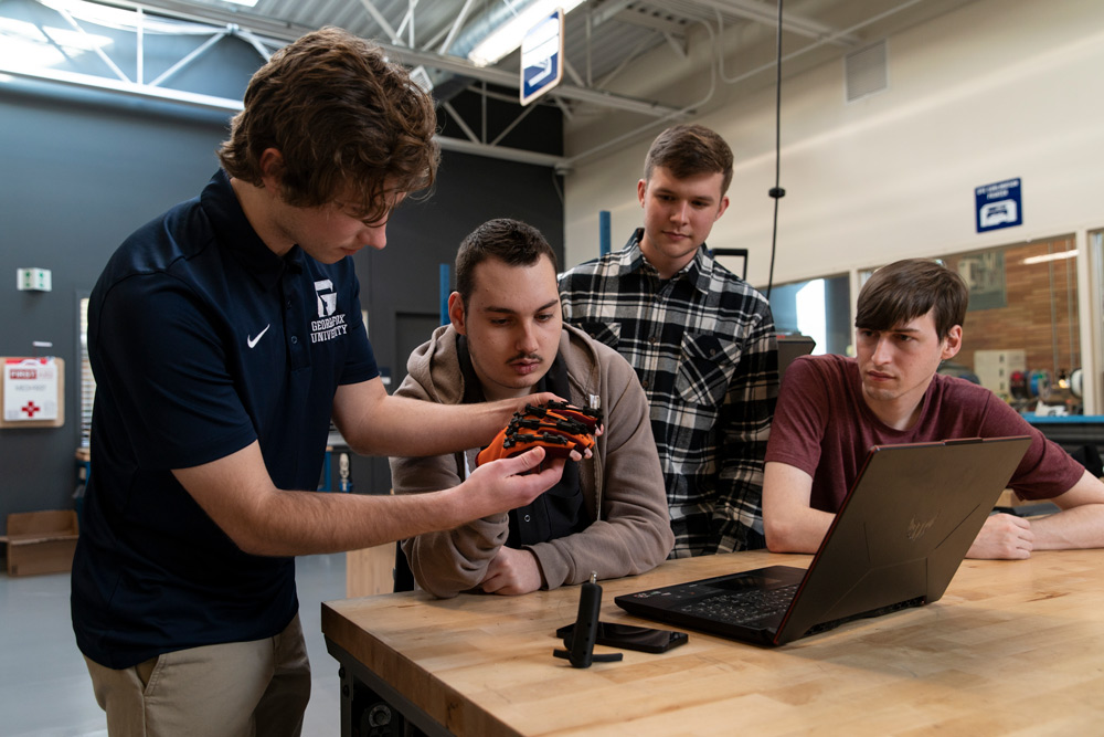 Engineering student adjusts the custom-built gauntlet on Brandon's hand