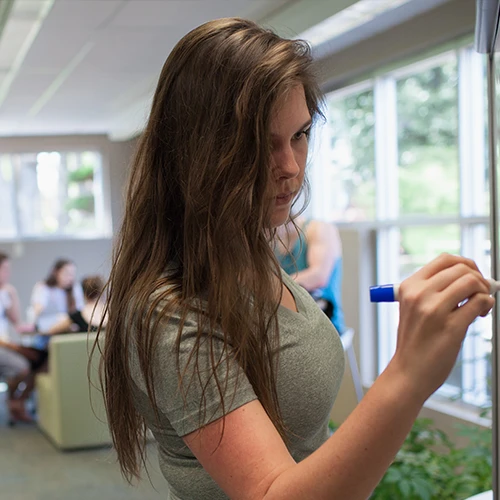 Student writing on a whiteboard 