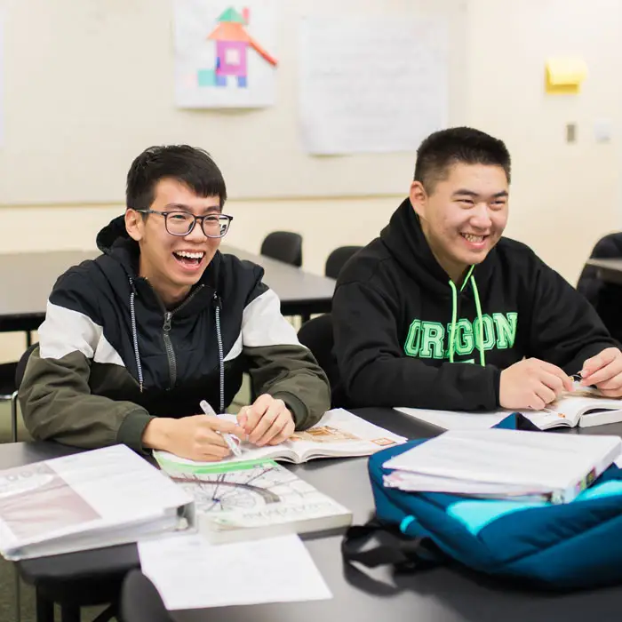 Two students sitting in a classroom learning English