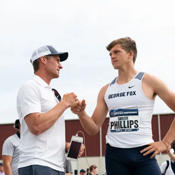 Track coach fist bumping one of the track athletes at a meet