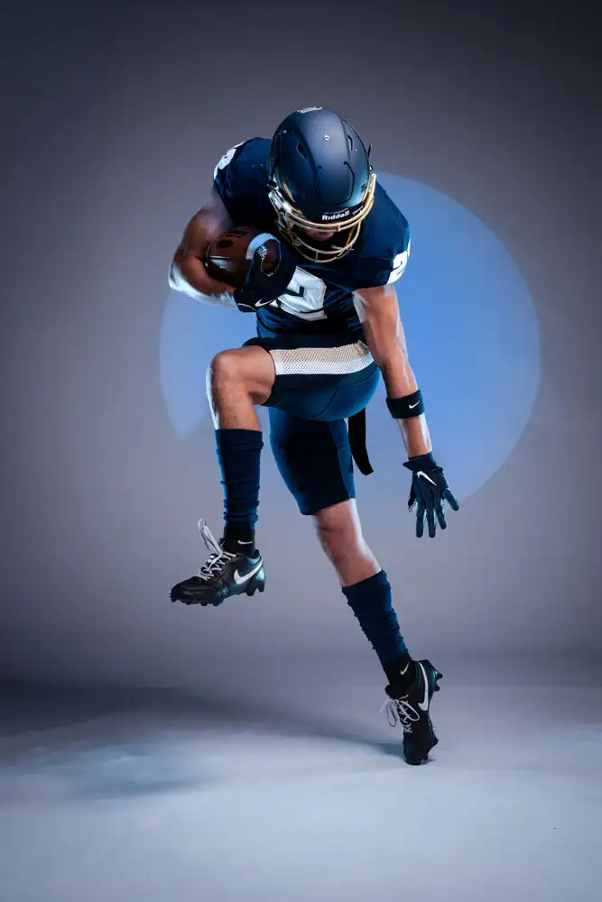 George Fox football player holding the ball and in position to fend an offender off