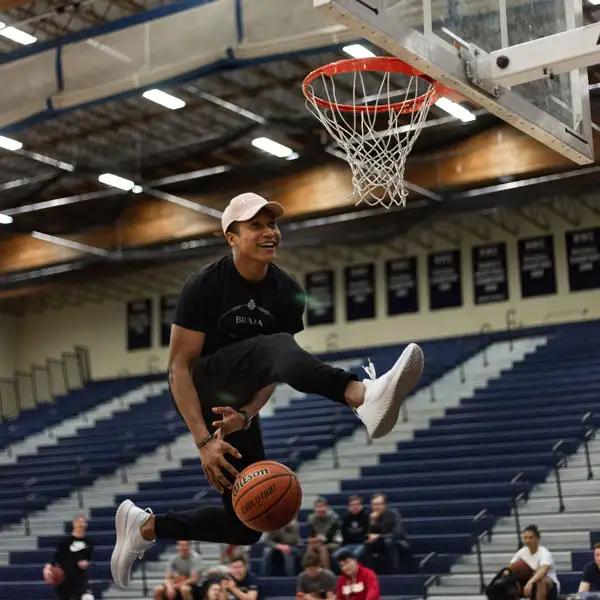 Student passing a basketball under his legs going in for a dunk