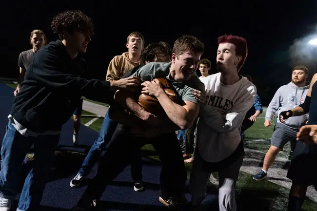 Students wresting on the football field at night over the Bruin Bear