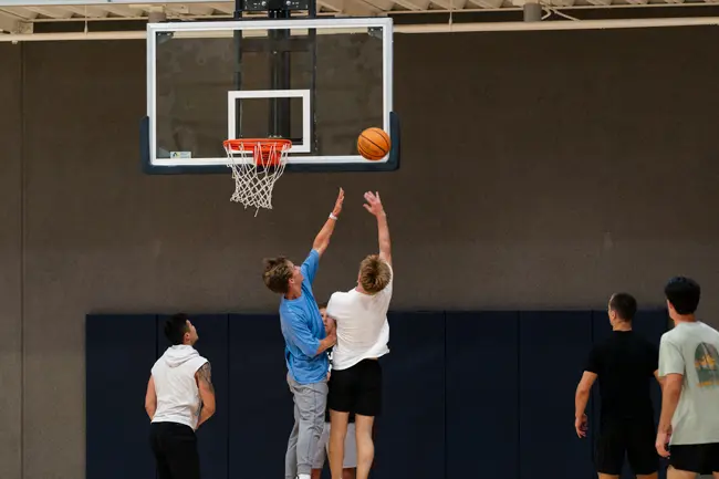 Student shooting a layup while another student attempts to block the shot