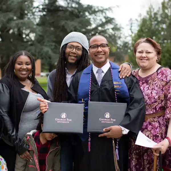 A father and son holding their George Fox diplomas next to one another