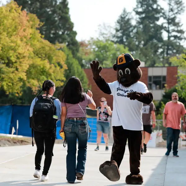 Two students walking through campus about to high five the Pennington mascot