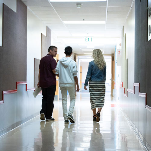 A teacher, counselor and student walk through a school hallway