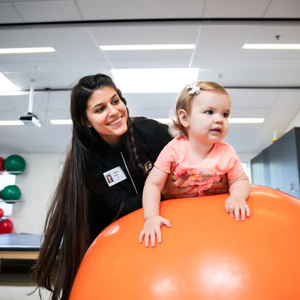 Student makes sure young child is safe playing on orange ball