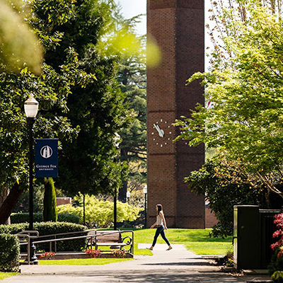 Student walking on campus in front of clock tower