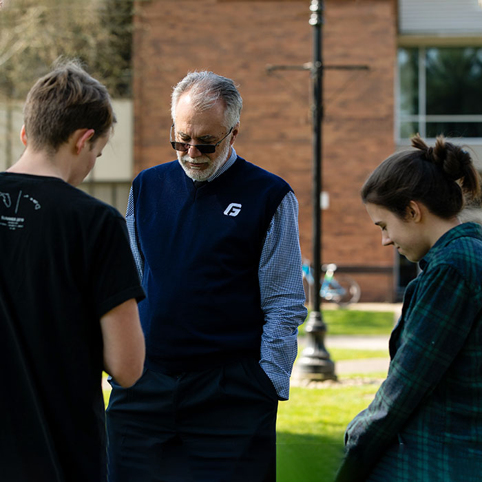 President, Robin Baker, prays with students on campus