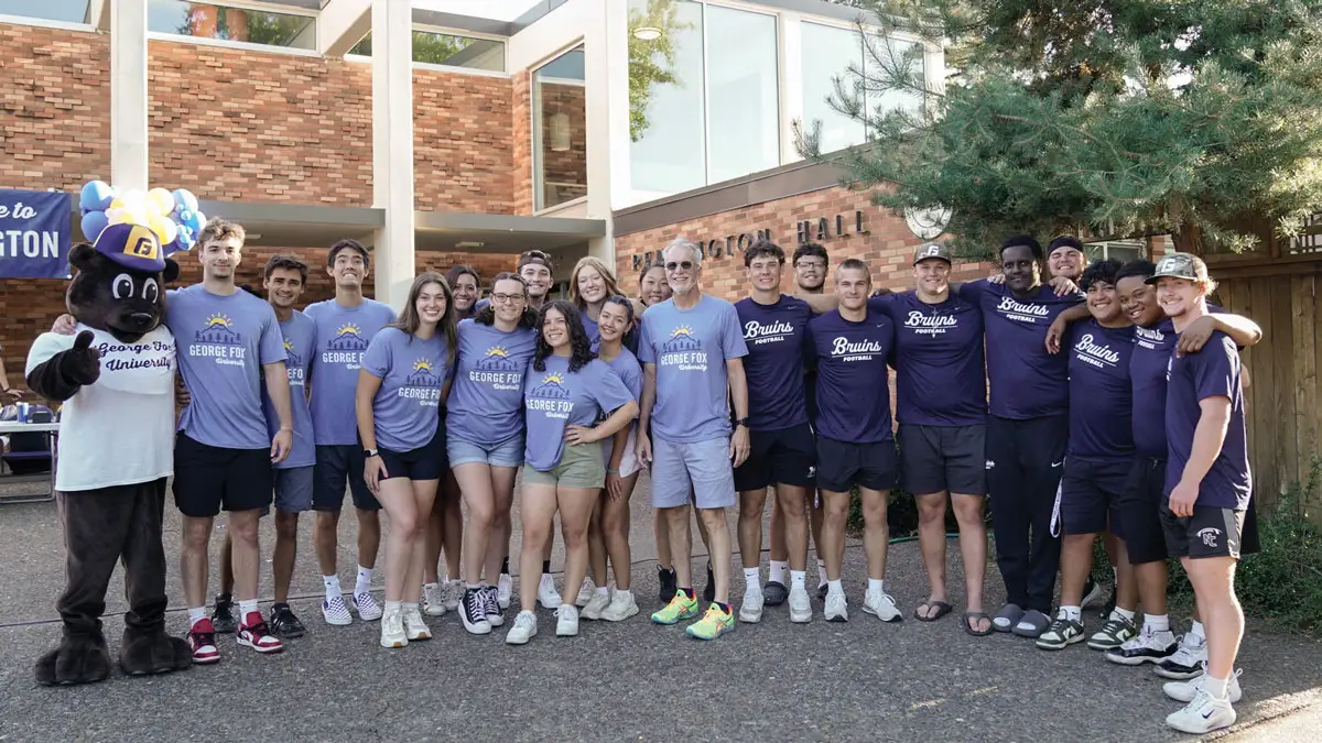 President Robin Baker standing amongst a cluster of students, all there to help freshmen move in.