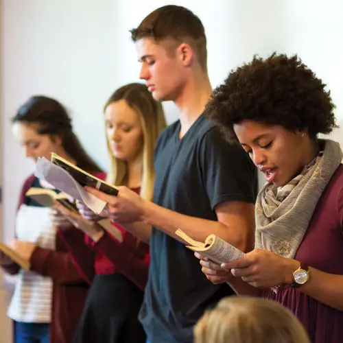 Honors students focused on a book while one student reads aloud