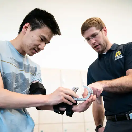 Student trying on the prosthetic device that was designed specifically for him