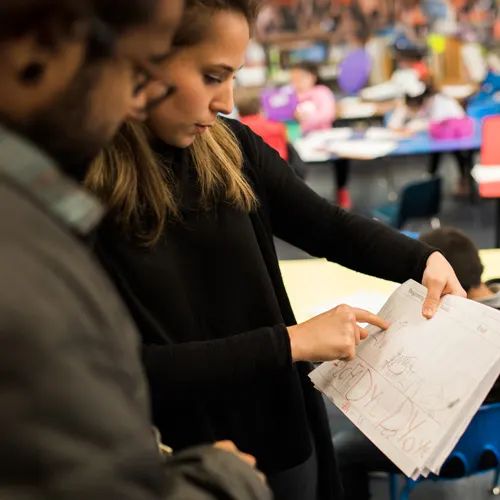 A student teacher compares notes with the classroom teacher