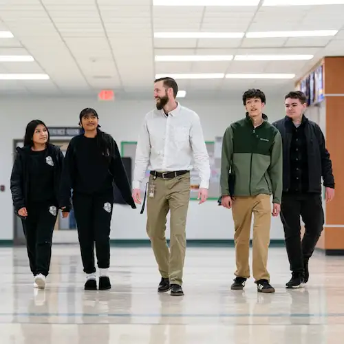 Roy walking through the school with 4 students