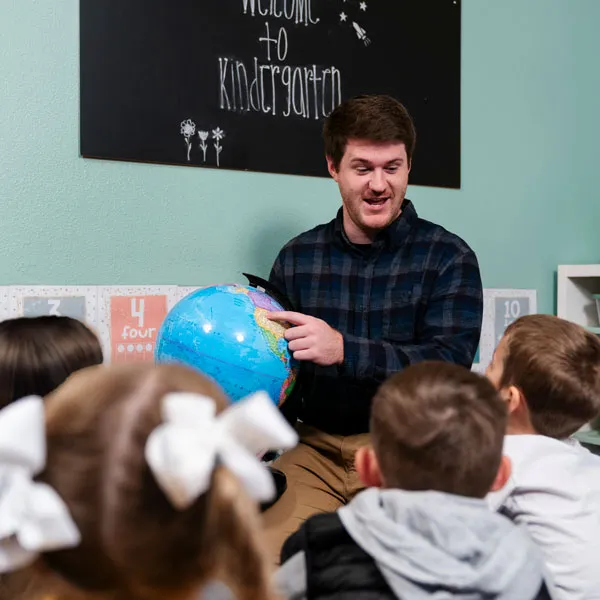Teacher points to a globe 