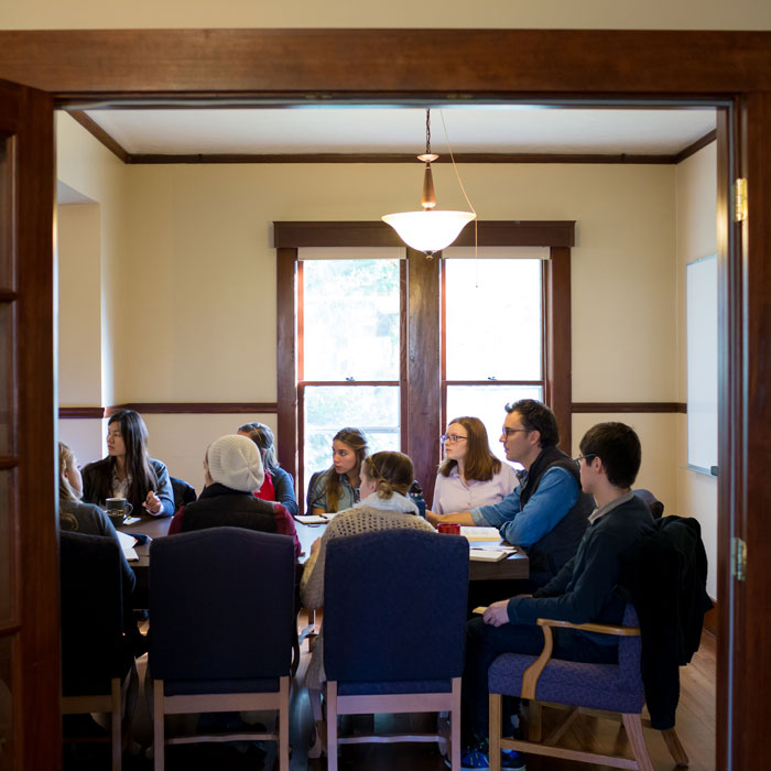 Students gathered around a table with professors