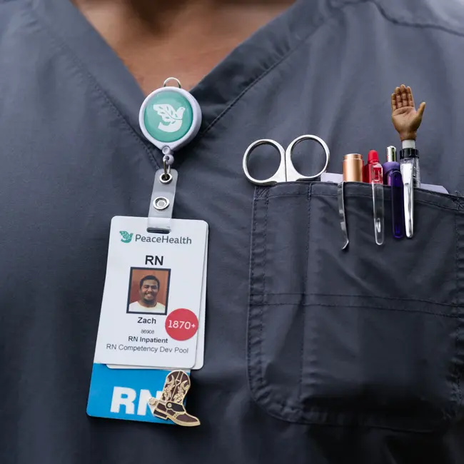 A close up of Zach's nurse's uniform including the shiny boot pin he received from the Kincaids