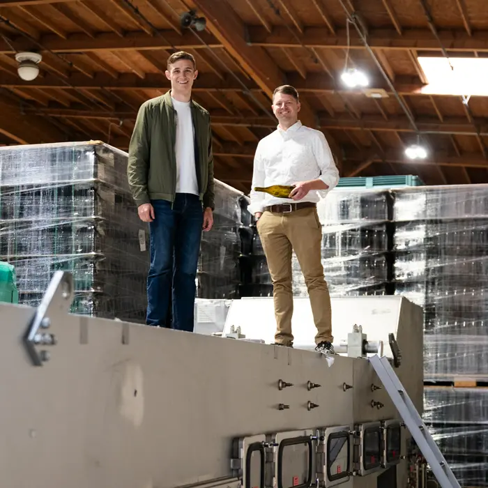 O’Hern and business partner Adam Rack stand atop a custom bottle washing machine in their Southeast Portland warehouse.