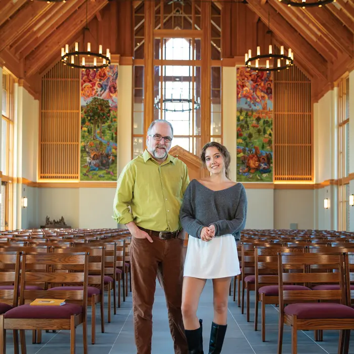 Tim and Alissa standing in the chapel in front of the murals they worked on