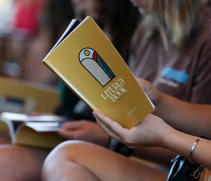 A yellow George Fox liturgy book being read by a student