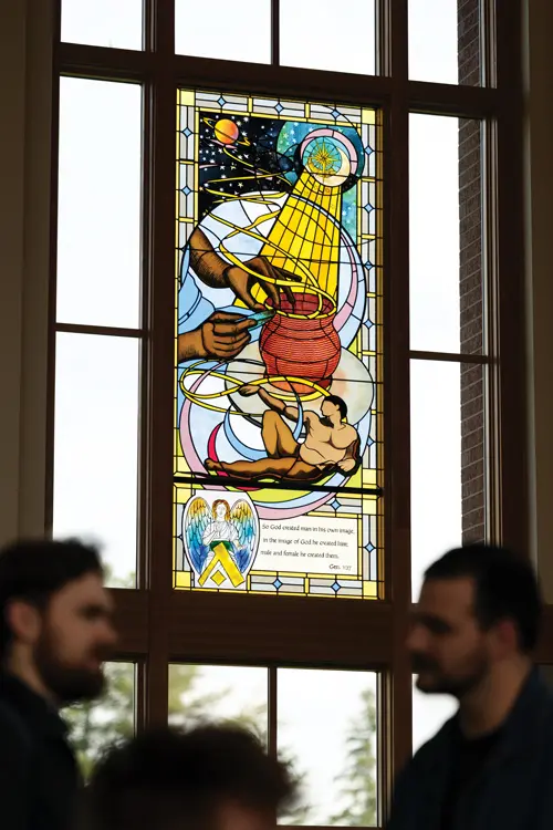 Light pouring through stained glass depicting the creation story